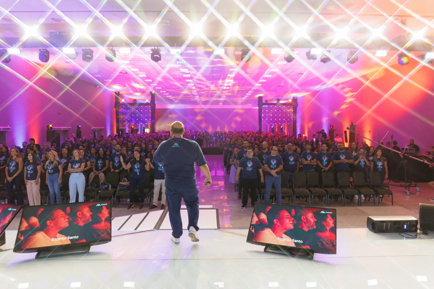 Central IT team gathered in front of the stage at an event lit in the brand colors